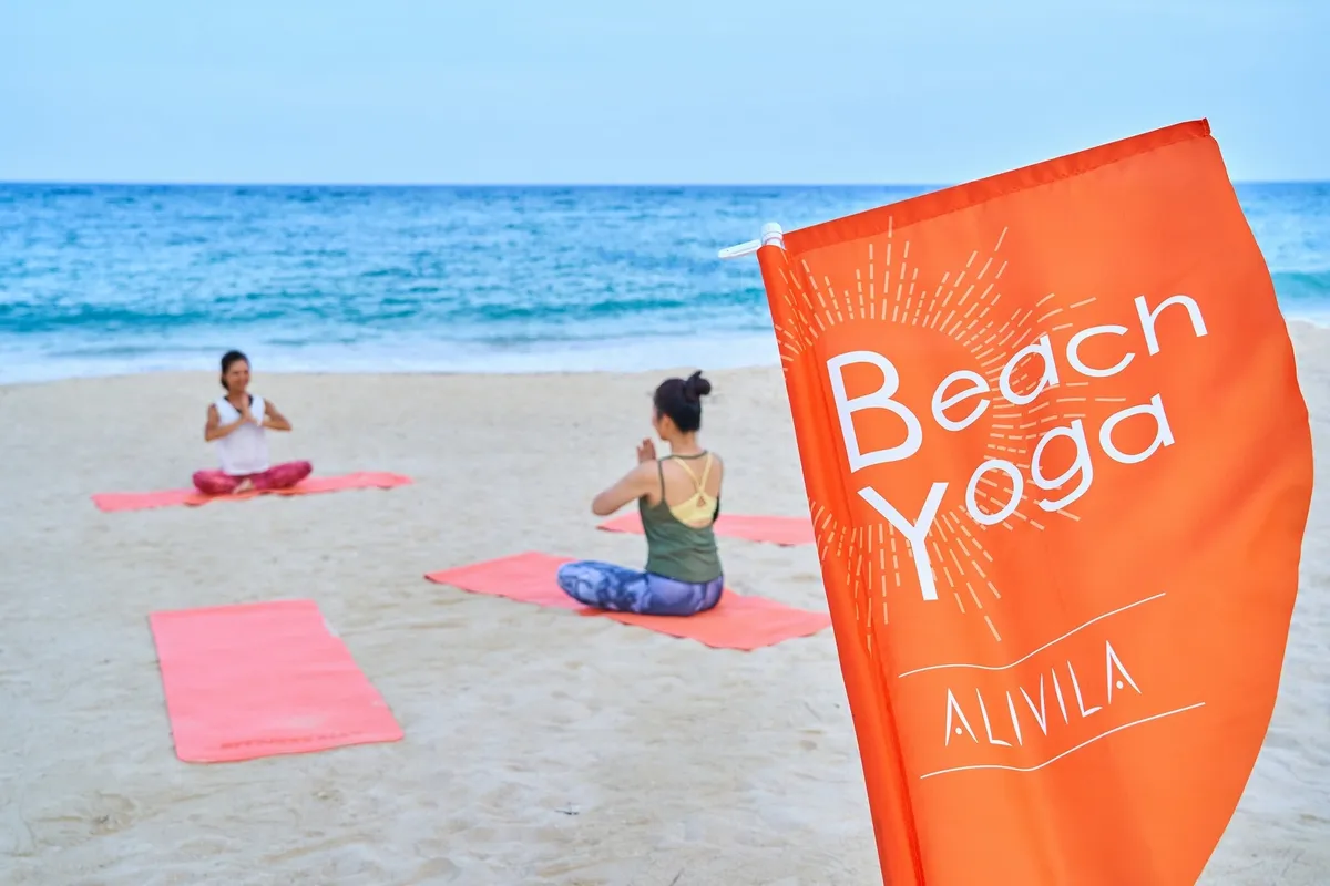 静かなビーチで朝日を浴びながら行うヨガ