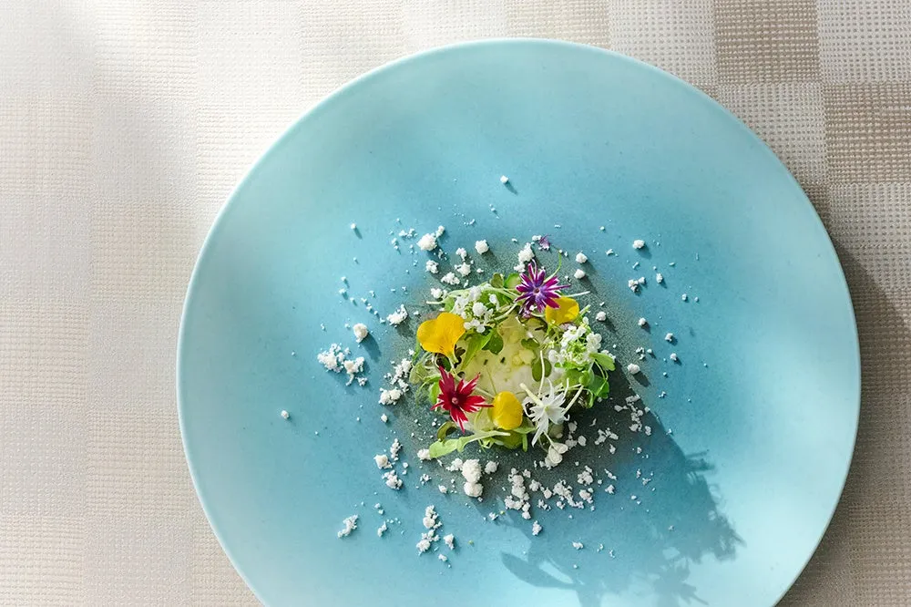 沖縄の青い海を思わせる皿に盛り付けられた、繊細で美しいフランス料理の一皿