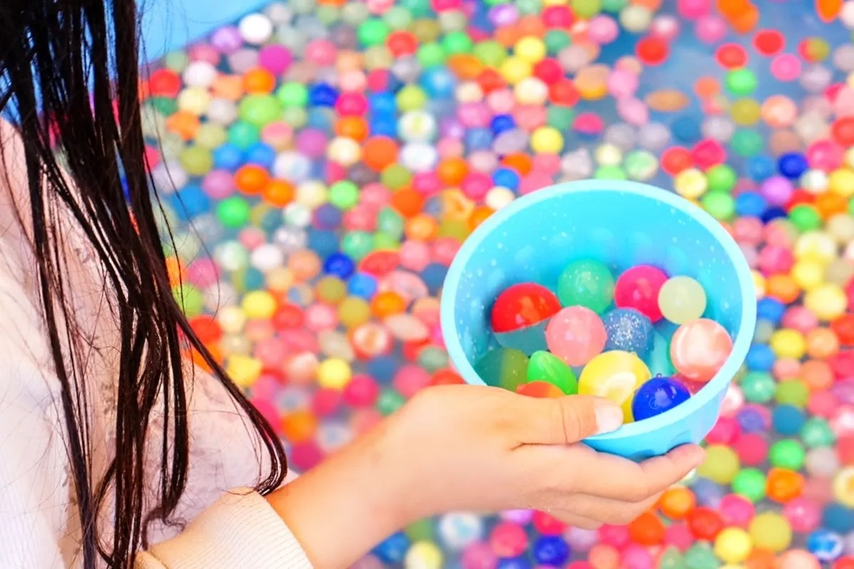 水面に浮かぶ色とりどりのスーパーボールをすくう様子