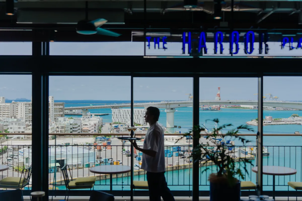 海が見えるレストランでサービスを行うスタッフと美しい港の夜景